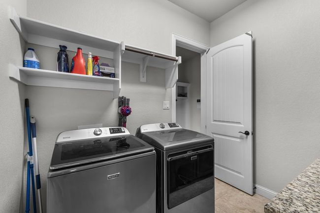 Clothes washing area featuring washing machine and clothes dryer, light tile patterned flooring, and baseboards | Image 11