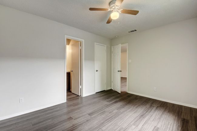 Unfurnished bedroom with wood finished floors, baseboards, a textured ceiling, and ceiling fan | Image 13