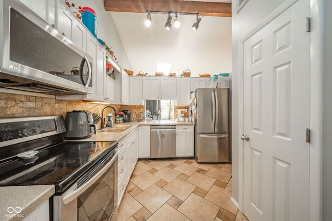 kitchen with stainless steel appliances, light countertops, tasteful backsplash, and white cabinets | Image 14