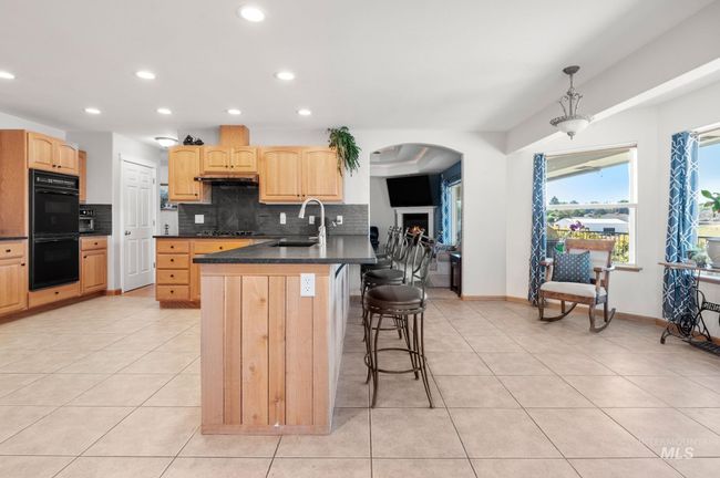 Kitchen with Large eating bar, black appliances, black honed granite countertops, decorative backsplash and recessed lighting | Image 16