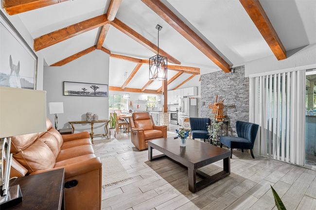 Living area featuring a chandelier, beamed ceiling, high vaulted ceiling, and wood finish floors | Image 9