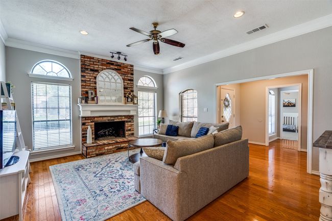 Living room featuring a ceiling fan, a fireplace, a healthy amount of natural light, and crown molding | Image 5