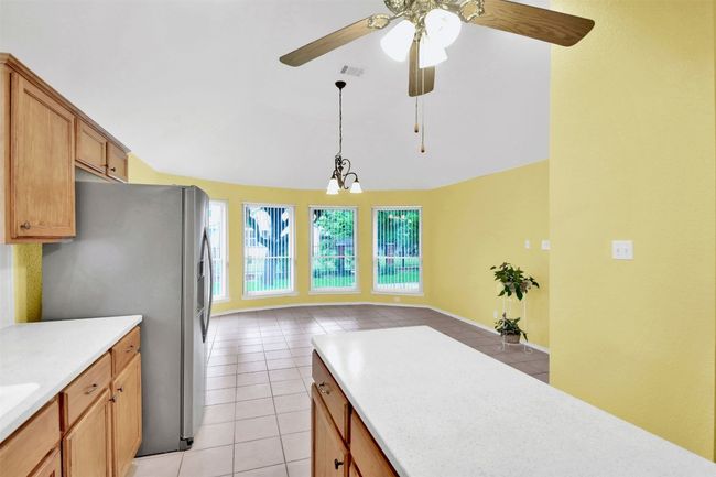 Kitchen with freestanding refrigerator, light tile patterned floors, light countertops, ceiling fan, and lofted ceiling | Image 18