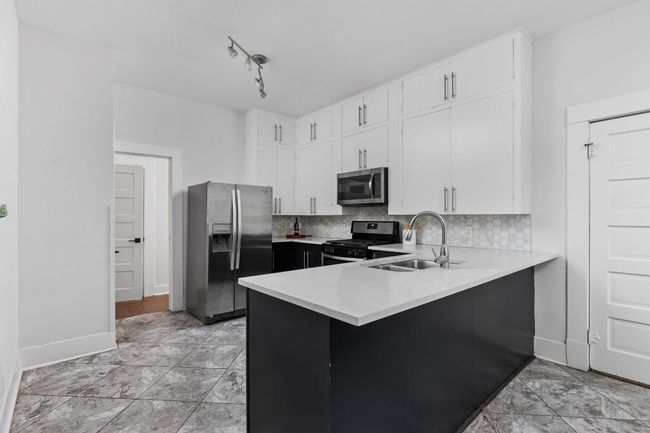 Kitchen featuring baseboards, light countertops, white cabinetry, stainless steel appliances, and a sink | Image 10