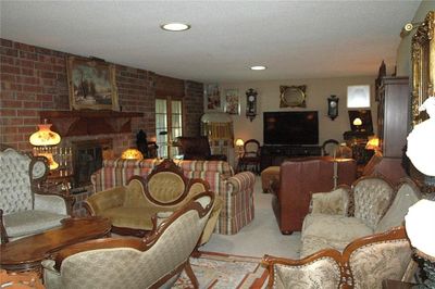 Living room featuring light carpet, a brick fireplace, and a textured ceiling | Image 3