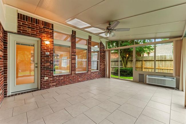 Surrounded by walls of glass, this light-filled sunroom offers beautiful backyard views and year-round enjoyment. With tile flooring, skylights, 2 sliding doors, a doggie door. and a ceiling fan, it's the perfect spot to relax, entertain, or create a flexible second living space. This fully enclosed space is both air conditioned and heated for year-round comfort. | Image 35
