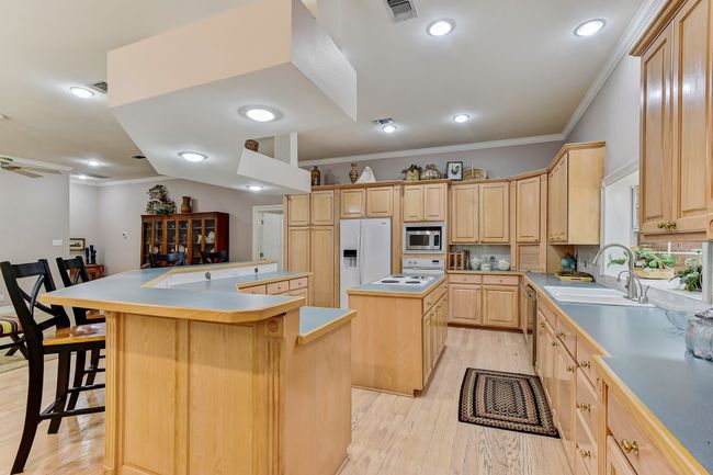 Kitchen with light brown cabinetry, a kitchen breakfast bar, stainless steel appliances, visible vents, and a center island | Image 11