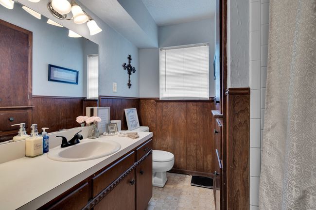 Full bathroom with wainscoting, toilet, vanity, wooden walls, and curtained shower | Image 19