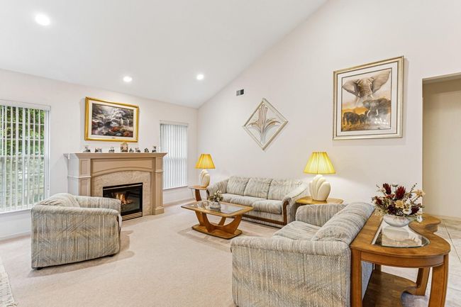 Living room featuring vaulted ceiling, a fireplace, baseboards, light colored carpet, and recessed lighting | Image 13
