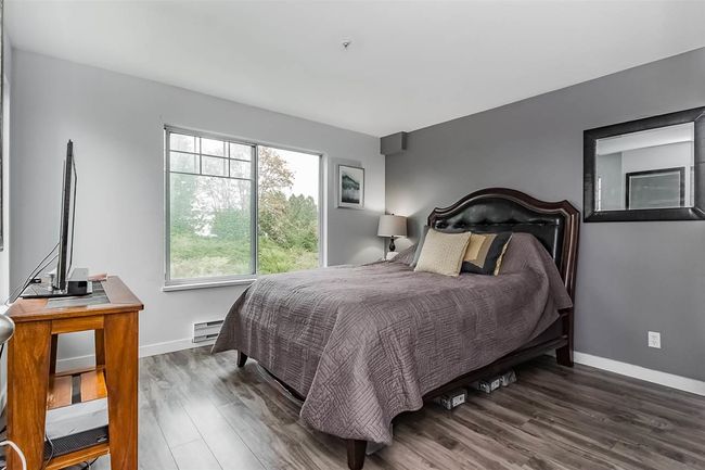 Bedroom featuring a baseboard radiator, baseboards, and wood finished floors | Image 12