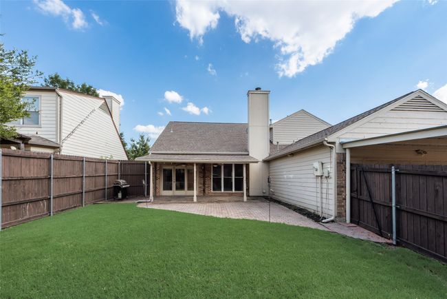 Rear view of house with brick siding, a fenced backyard, a chimney, a patio, and a shingled roof | Image 26