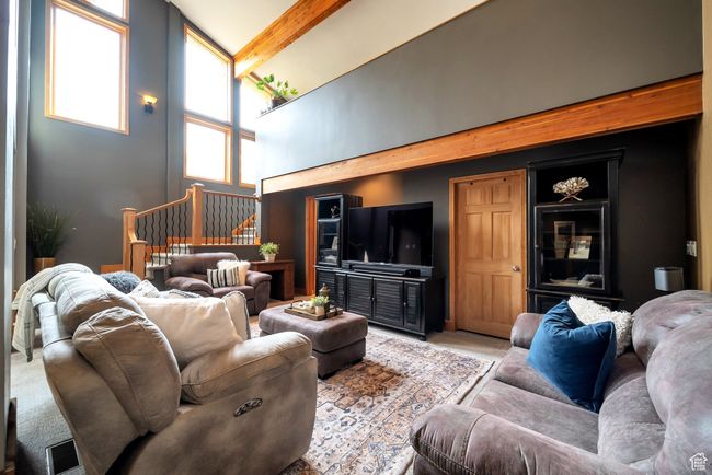 Carpeted living room featuring beam ceiling, stairway, and high vaulted ceiling | Image 17