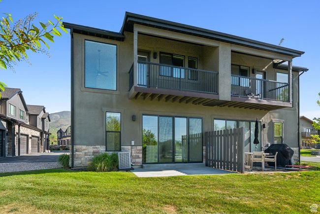 Rear view of property with a balcony, stone siding, stucco siding, central AC, and a patio area | Image 46