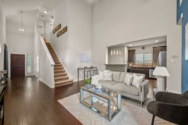 Living area with a towering ceiling, baseboards, dark wood finished floors, and stairs | Image 6
