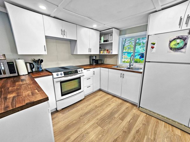 Kitchen featuring butcher block countertops, freestanding refrigerator, a sink, and electric range oven | Image 8