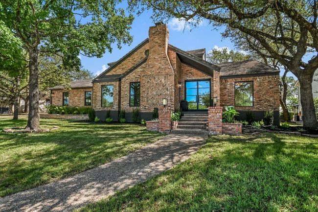 Brick and stucco home with slate roof, wrought iron front door and lush landscaping | Image 15