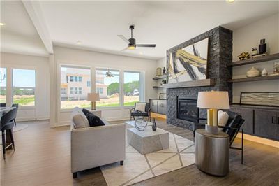 Living room with light hardwood / wood-style flooring, a fireplace, ceiling fan, and a healthy amount of sunlight | Image 3