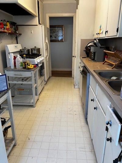 Kitchen with white cabinetry, dishwashing machine, range, and sink | Image 3