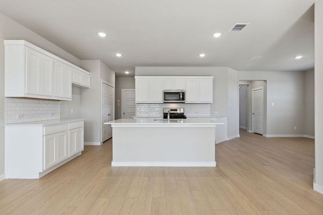 Kitchen featuring appliances with stainless steel finishes, backsplash, light countertops, light wood-style flooring, and recessed lighting | Image 6