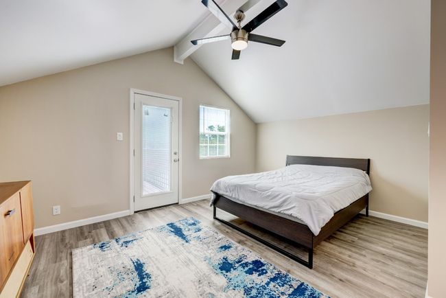 Bedroom featuring baseboards, lofted ceiling with beams, ceiling fan, wood finished floors, and access to outside | Image 9