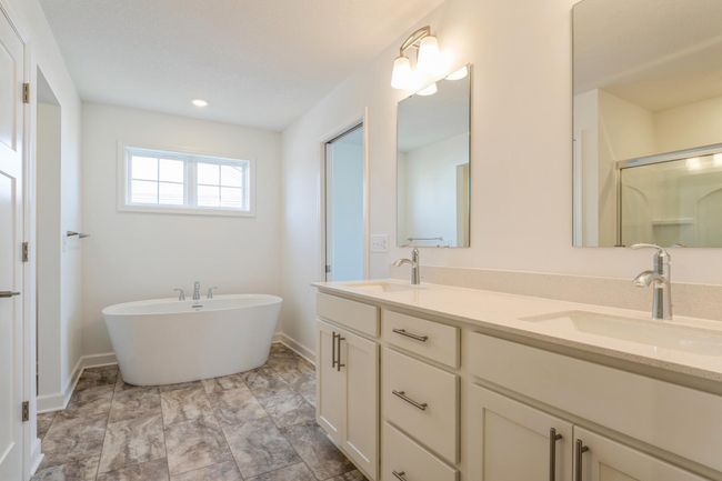 Photo is of the actual home. An extension of the primary bedroom, this private and spacious bath contains a double-vanity, a soaking tub, a shower and a walk-in closet. | Image 14