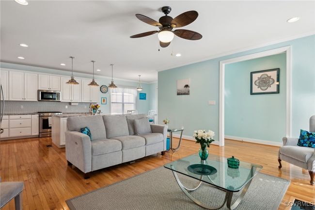 Living room with ceiling fan and recessed lighting. Through the encased opening to the left is an extra deep storage closet and to the right is the primary bedroom. | Image 12