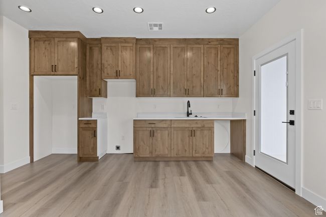 Kitchen featuring light countertops, a sink, light wood-style floors, and visible vents | Image 16