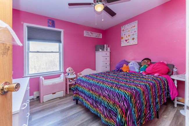 Bedroom featuring a baseboard radiator, a ceiling fan, and wood finished floors | Image 38