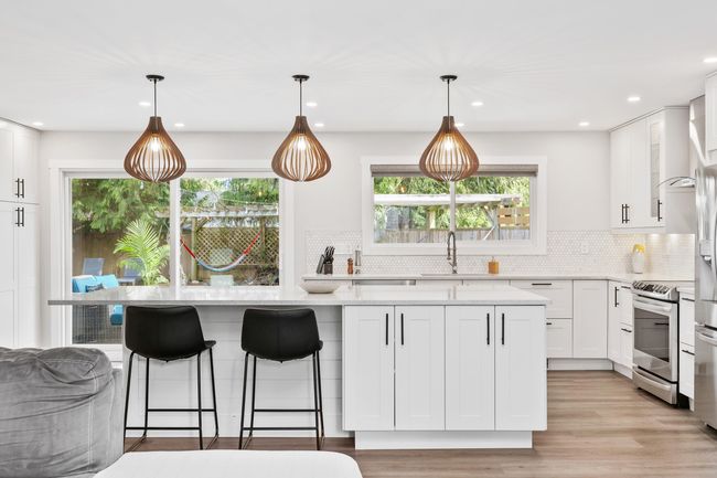 Kitchen featuring white cabinets, a wealth of natural light, stainless steel range with electric cooktop, and light stone countertops | Image 9
