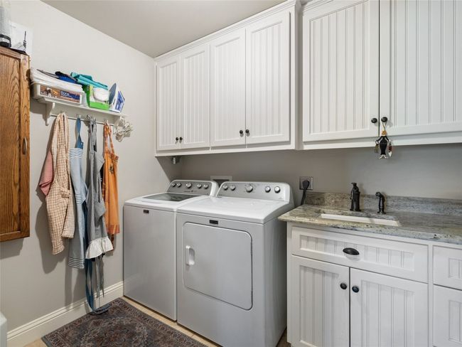 Utility room has a sink, built-in ironing board and plentiful storage. | Image 35