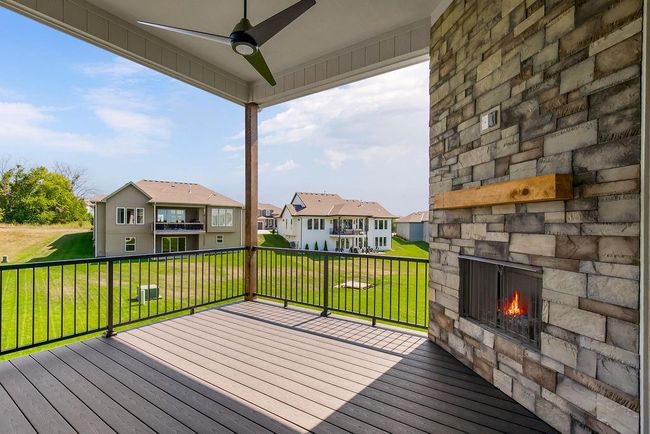 Deck with an outdoor stone fireplace, a residential view, ceiling fan, and a lawn | Image 17