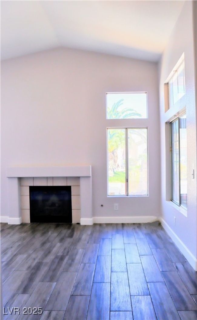 living room featuring baseboards, vaulted ceiling, wood finished floors, and a fireplace | Image 7