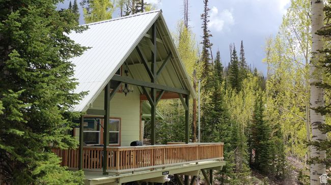 Back of property with a metal roof, a wooden deck, and a view of trees | Image 49