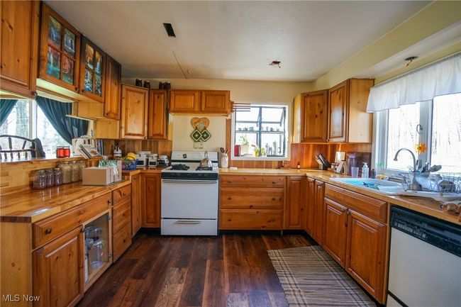 Kitchen featuring brown cabinets, dark wood-style flooring, a sink, and white appliances | Image 7