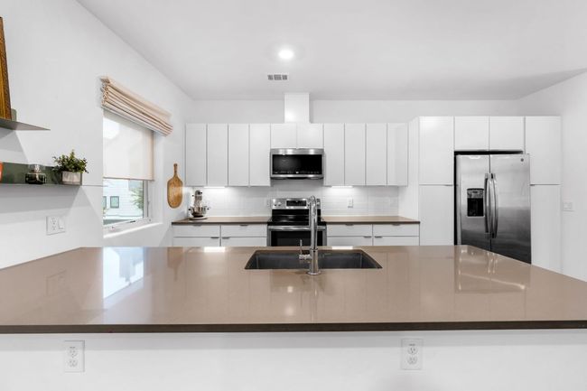 Kitchen with white cabinetry, tasteful backsplash, appliances with stainless steel finishes, visible vents, and dark countertops | Image 10