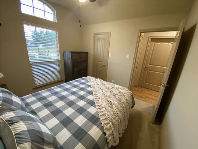 Bedroom featuring light wood-style floors, lofted ceiling, and ceiling fan | Image 9