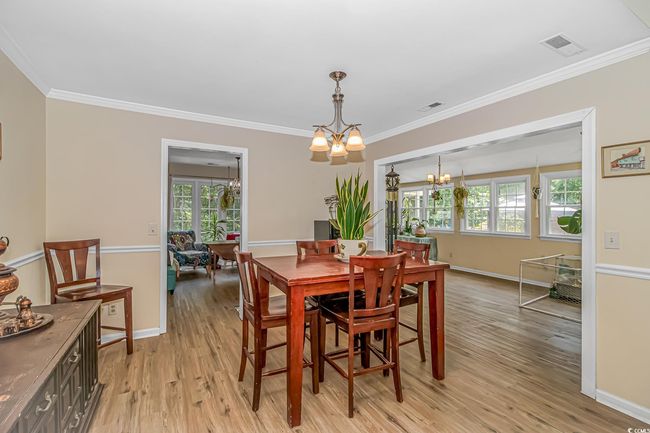 Dining space featuring a chandelier, healthy amount of natural light, light wood-style floors, and ornamental molding | Image 5