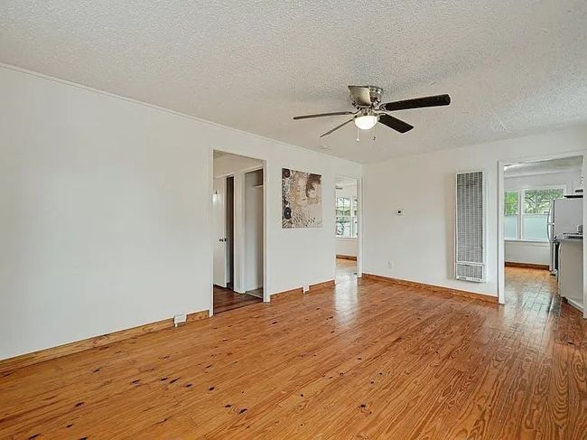Unfurnished room featuring a heating unit, a textured ceiling, a ceiling fan, plenty of natural light, and wood finished floors | Image 5