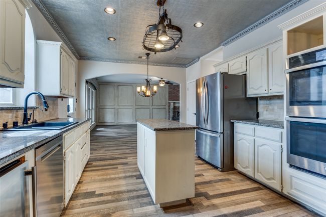 Kitchen with a sink, wood finished floors, a center island, stainless steel appliances, and arched walkways | Image 14