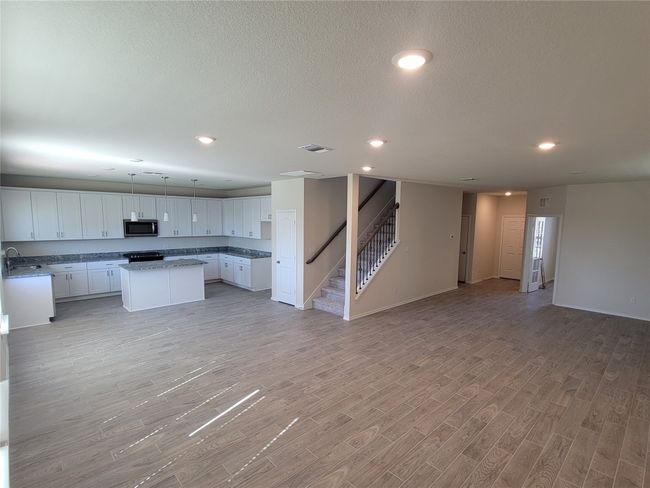 Kitchen with visible vents, stainless steel microwave, a sink, open floor plan, and a center island | Image 4