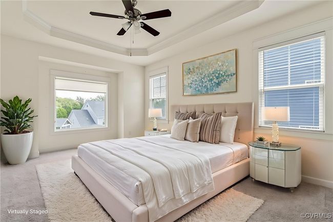 Bedroom with light colored carpet, a raised ceiling, crown molding, and a ceiling fan | Image 26