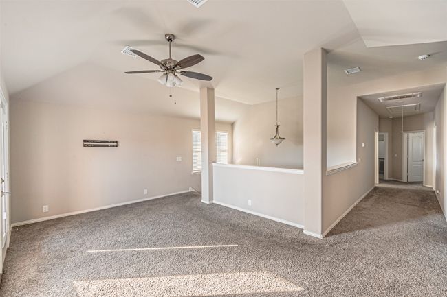 Unfurnished living room featuring attic access, carpet, a ceiling fan, lofted ceiling, and baseboards | Image 28