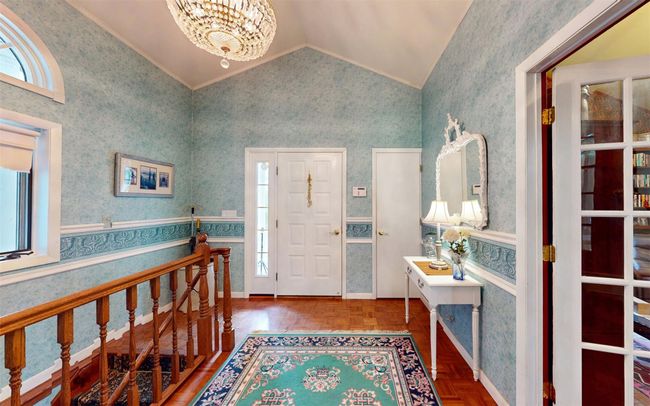 Foyer featuring lofted ceiling, wallpapered walls, a chandelier, and crown molding | Image 7
