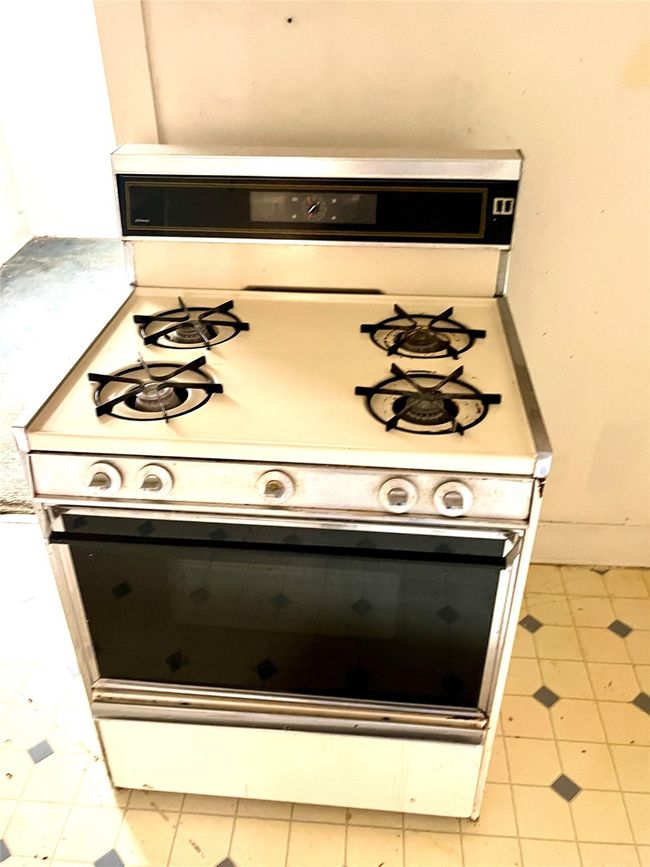 Kitchen view of white gas stove, tile patterned floors, and light countertops | Image 12