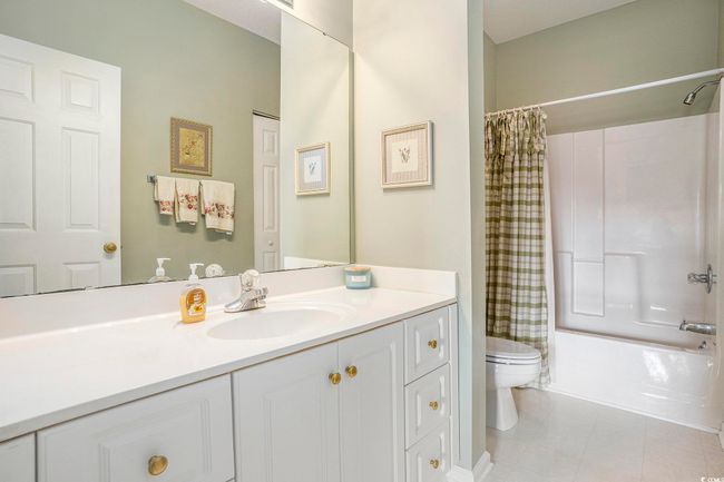 Full bath featuring toilet, vanity, shower / bath combination with curtain, and tile patterned flooring | Image 14