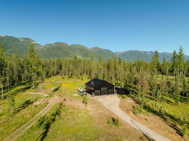 View from above of property with a heavily wooded area and mountains | Image 74