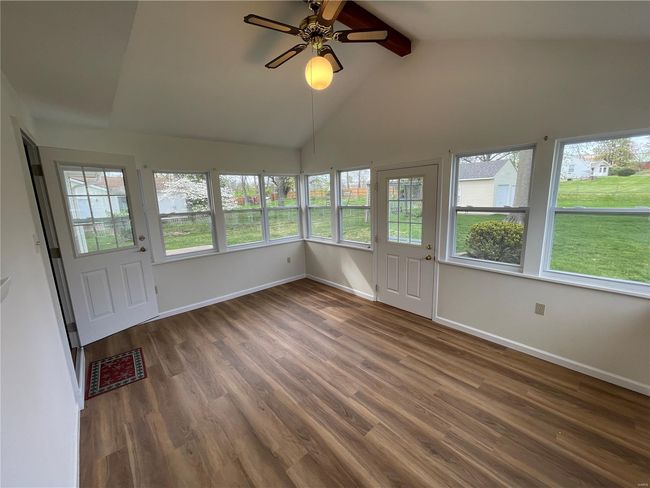 Unfurnished sunroom with a healthy amount of sunlight, wood finished floors, visible vents, and beam ceiling | Image 40