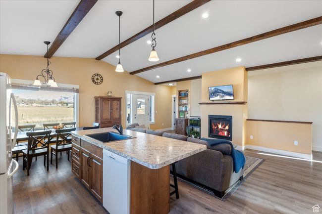 Kitchen with vaulted ceiling with beams, light countertops, a glass covered fireplace, white appliances, and a sink | Image 14