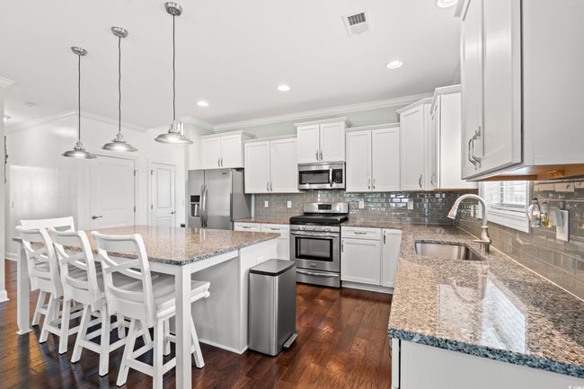 Kitchen featuring stainless steel appliances, ornamental molding, white cabinets, a kitchen island, and tasteful backsplash | Image 10