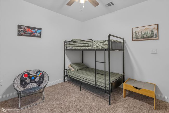Carpeted bedroom with visible vents, baseboards, and ceiling fan | Image 23